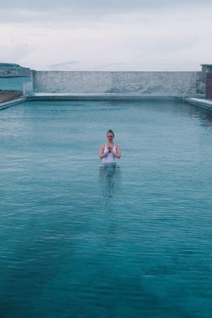 Woman in pool near sea and hills on shore
