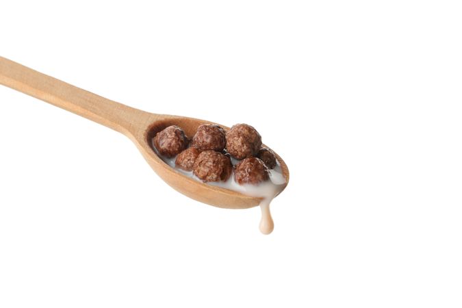 Spoon with corn balls and milk isolated on plain background
