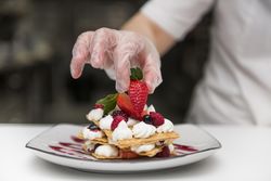 Chef putting strawberry on dessert