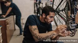 Man fixing a bicycle in a repair shop inside 0ymPL0