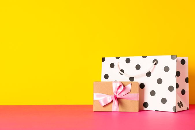 Paper bag with present on multicolor background, space for text