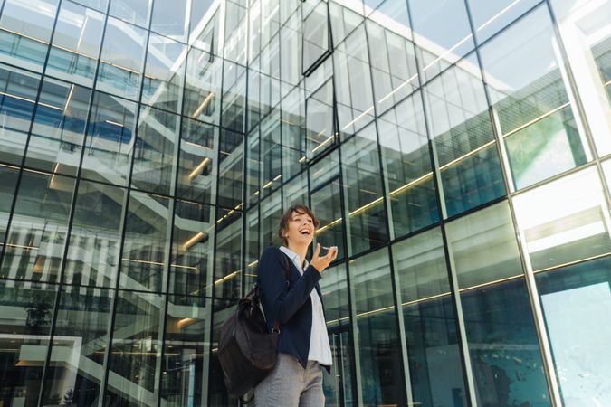 Smiling entrepreneur browsing smartphone outside office building