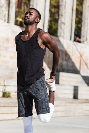 Black sportsman stretching on basketball court