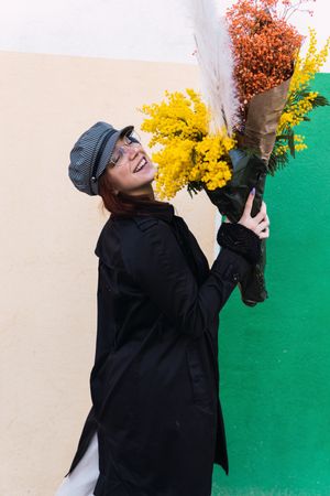 Woman with flowers smiling against colorful wall