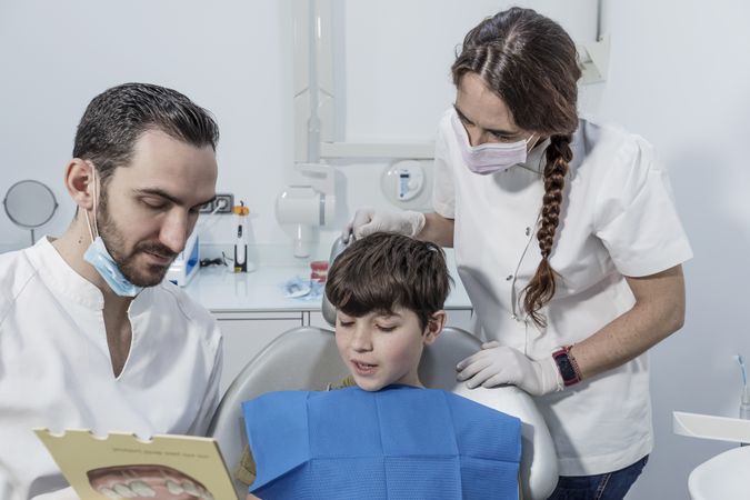 Dentist shows boy an example of installing braces on his teeth