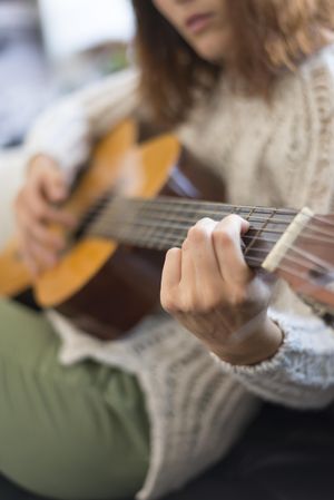 Female hand on fretboard of guitar, vertical
