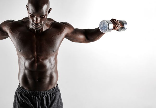 Shot of a male model exercising with dumbbells on grey background