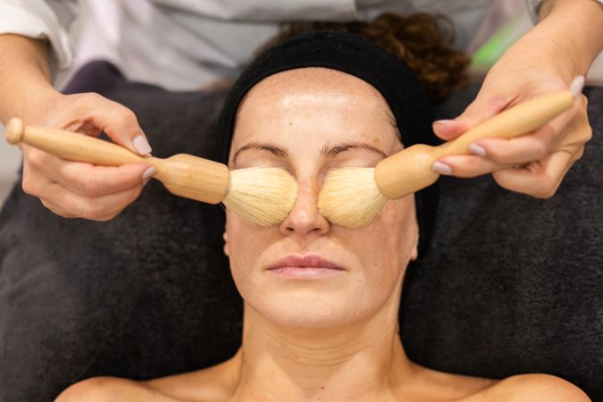 Woman having relaxing facial with brushes cleansing nose