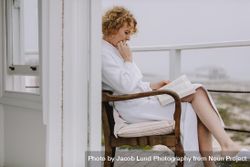 Woman reading a book sitting in balcony 0WOaEj