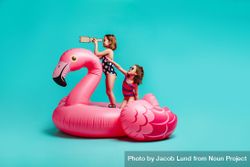 Two girls having fun on inflatable toy flamingo 4NKmDb
