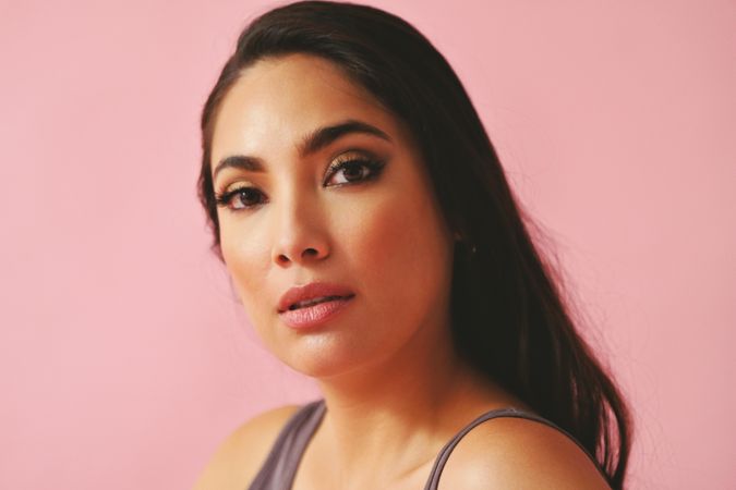 Serious Hispanic woman looking at camera in pink room
