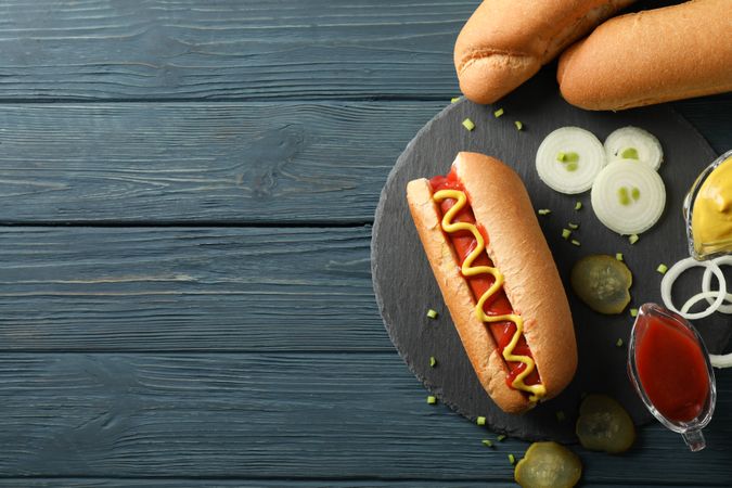 Tasty hot dog and ingredients on wooden background