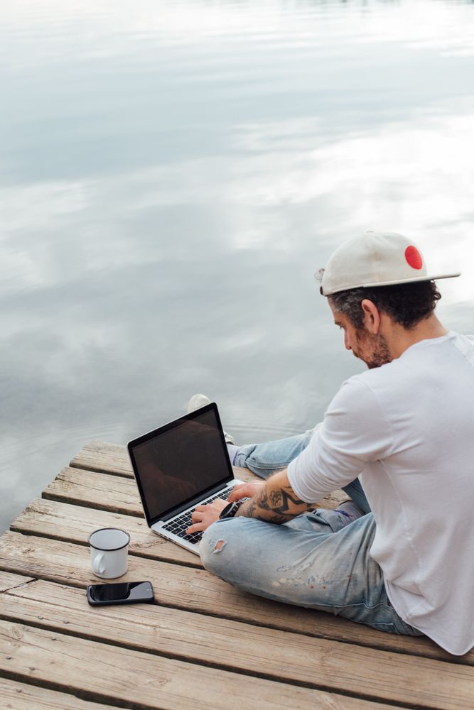 Man with laptop and coffee on pier