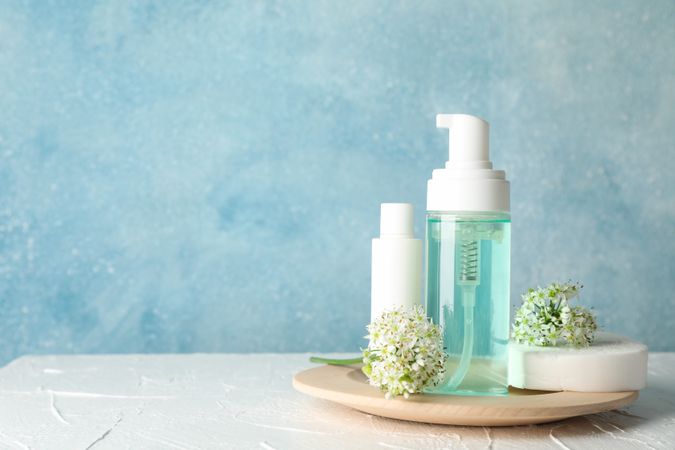 Lotion, allium flowers, sponge and cream on blank background, copy space
