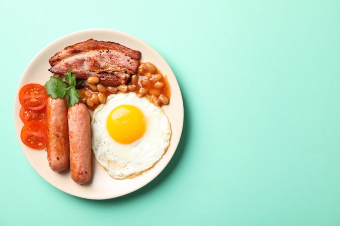 Top view of breakfast plate on green background, copy space