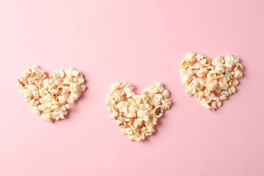 Flat lay composition with popcorn hearts on pink background, space for text