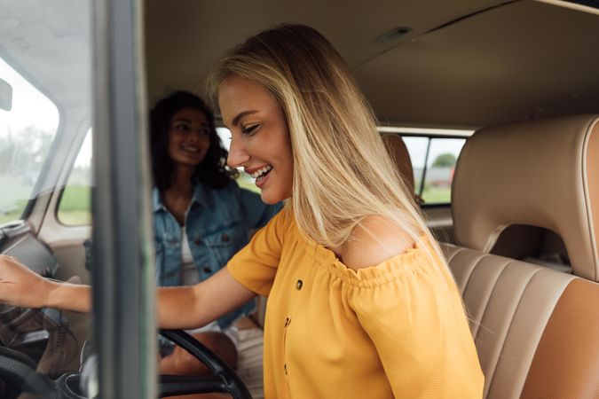 Blonde woman driving car with friend sitting in the passenger seat