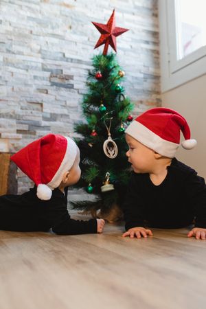 Happy babies near Christmas tree and gifts