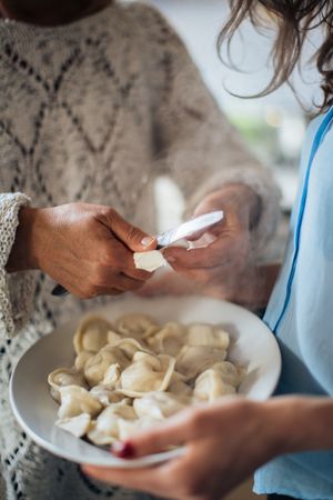 Cropped image of two women holding a plate of dumplings
