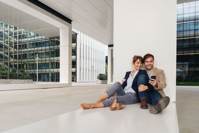 Businesspeople hugging and using smartphone on street