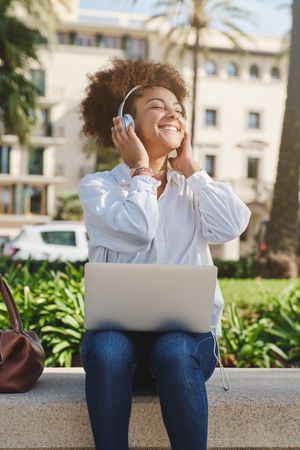Black female freelancer working and listening to music on street