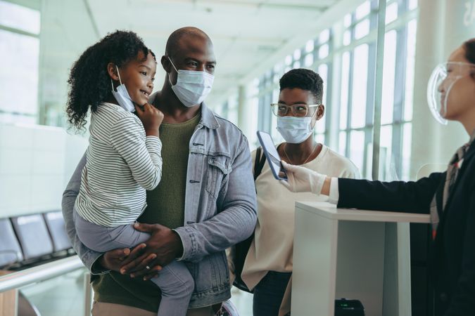 Tourist family at departure gate with airlines attendant during pandemic