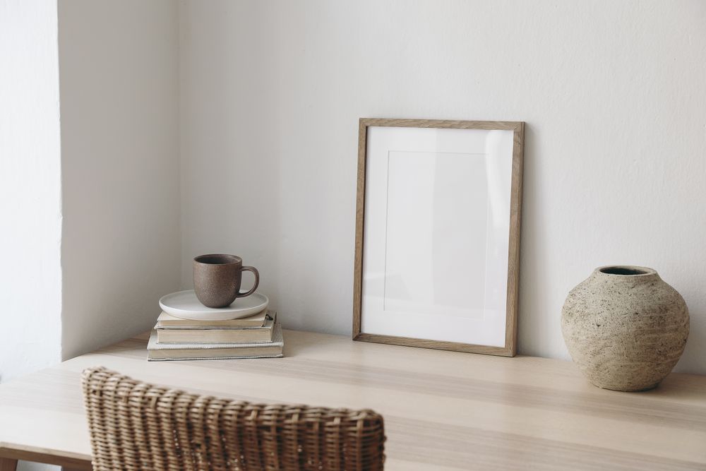 Mock up poster on table in neutral space with vase, eucalyptus leaves, books and coffee