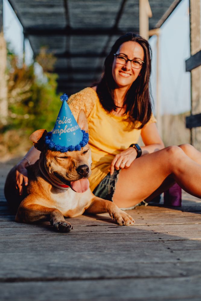 Casual young woman resting next to brown dog with party hat