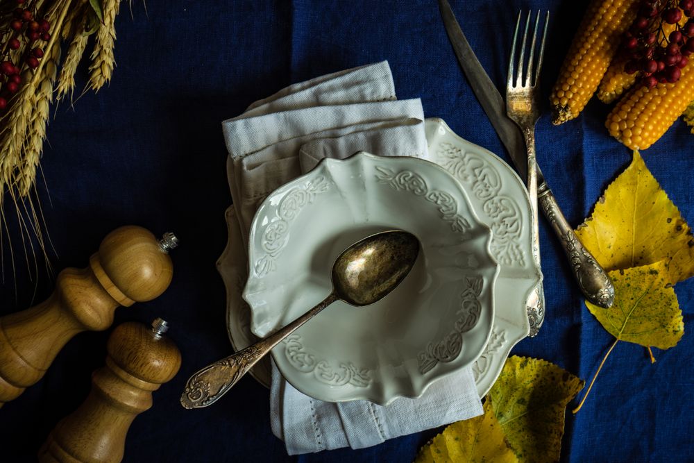 Top view of delicate porcelain bowl on blue table cloth with autumn decor