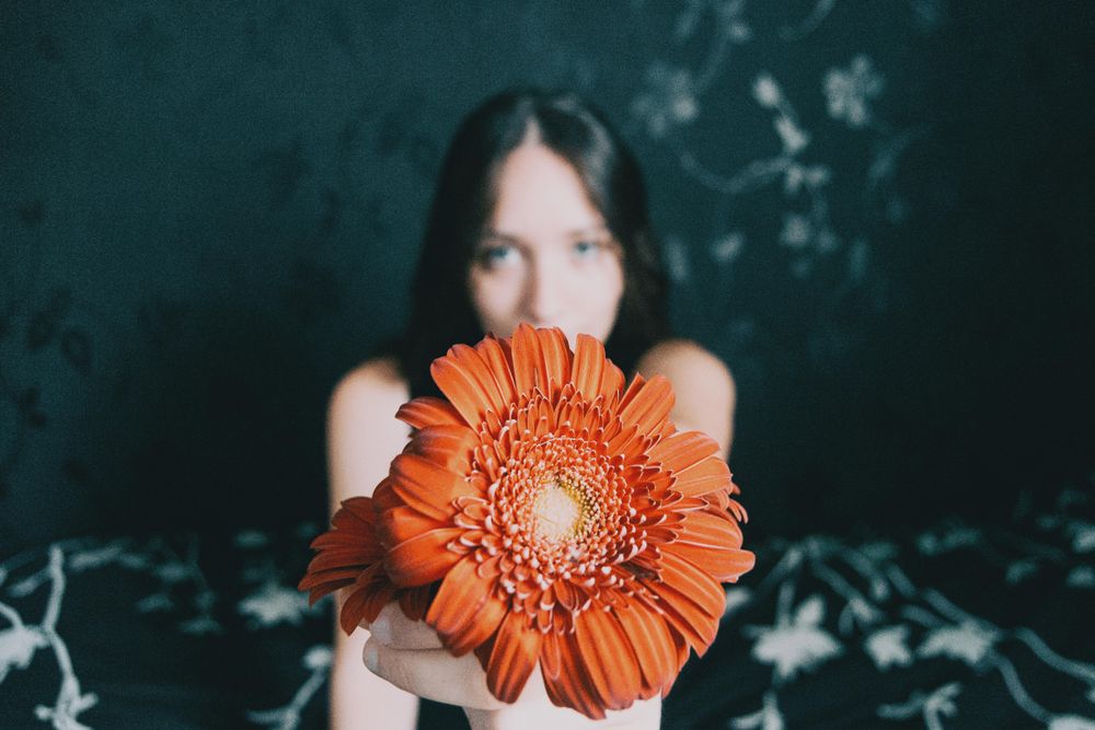 Studio portrait of woman with blue eyes holding a gerbera flower