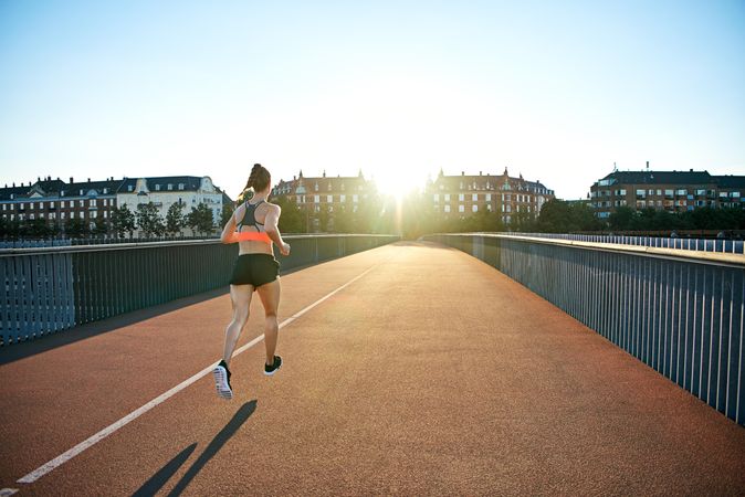 Fit woman working out on bridge with morning sun