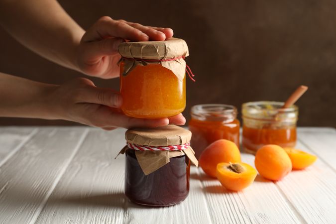 Female hands hold glass jar with apricot jam. Preparing jam