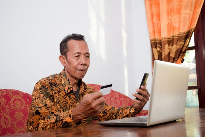 Older man holds blank credit card doing payment online