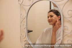 Woman applying moisturizer cream on face bDjVPA