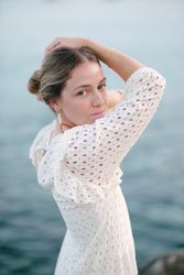 Stylish calm woman touching head and looking at camera at seaside
