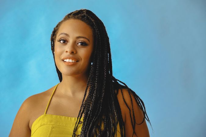 Portrait of confident female with long braided hair in yellow shirt, copy space