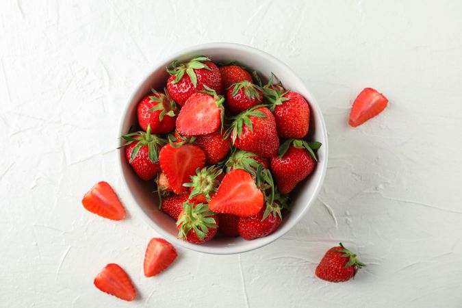Bowl with fresh strawberries on light background, space for text. Summer sweet fruits and berries