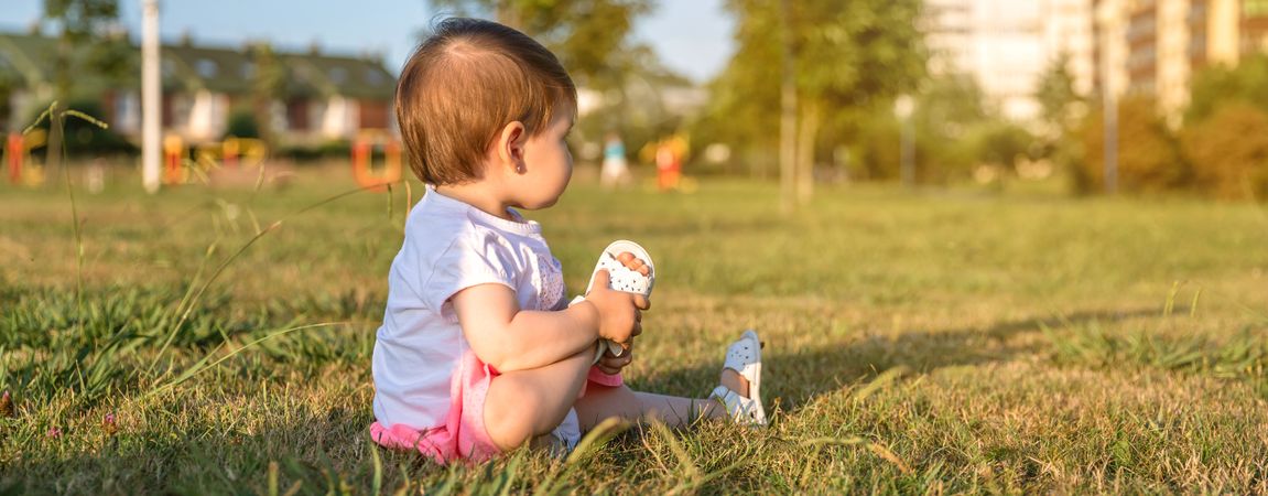 Happy baby girl playing sitting on a grass park