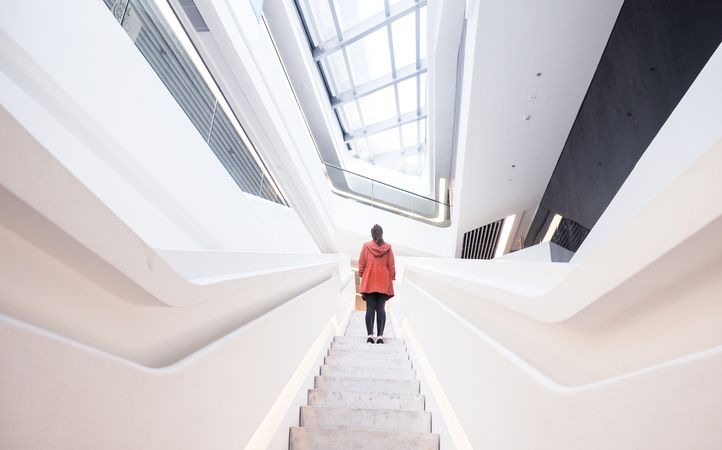 Back view of woman in red coat standing on staircase