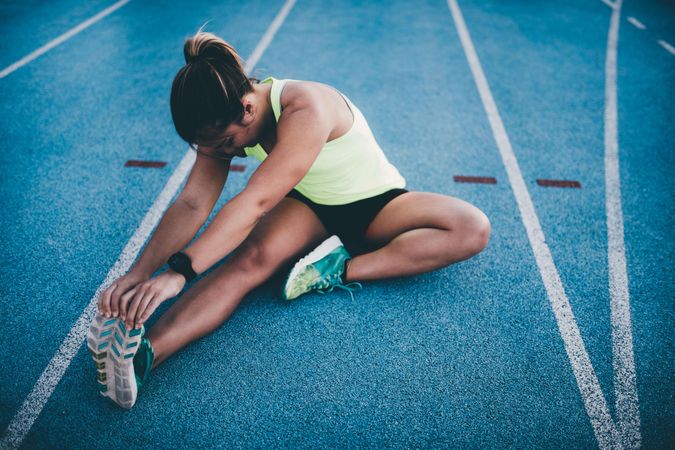 Young woman stretching on a track field