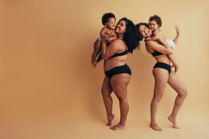 New postpartum mothers confidently wearing dark undergarments and holding their infants