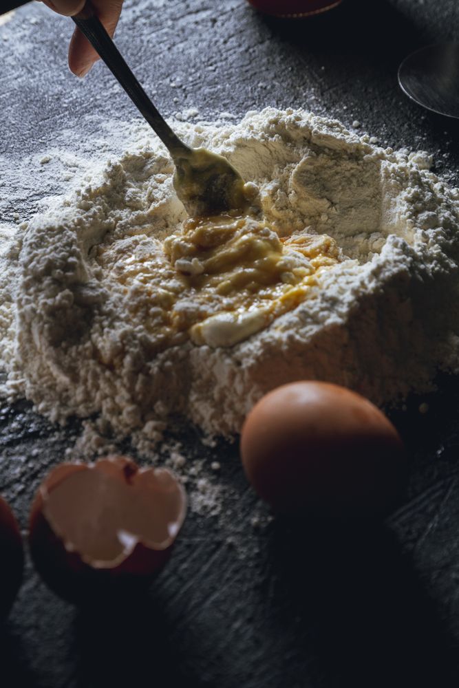 Cook preparing dough with egg and flour