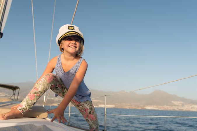 Smiling girl sitting on deck of yacht in sea