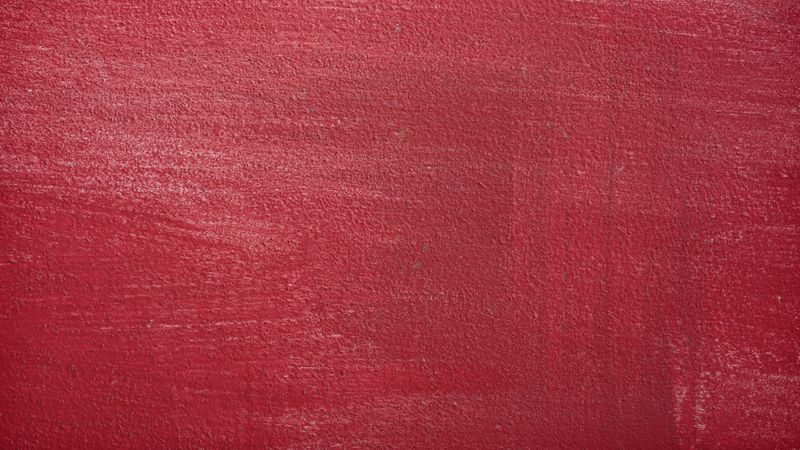 Dark red concrete wall with rough texture and subtle light reflections