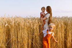 Young mother with little sons standing on wheat field in countryside