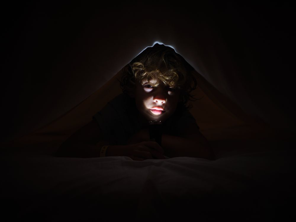 Boy with flashlight in darkness