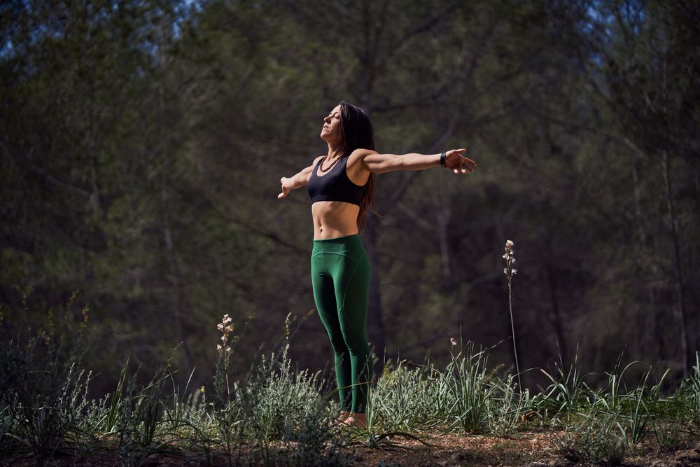 Graceful Hispanic woman meditating in mountains with closed eyes