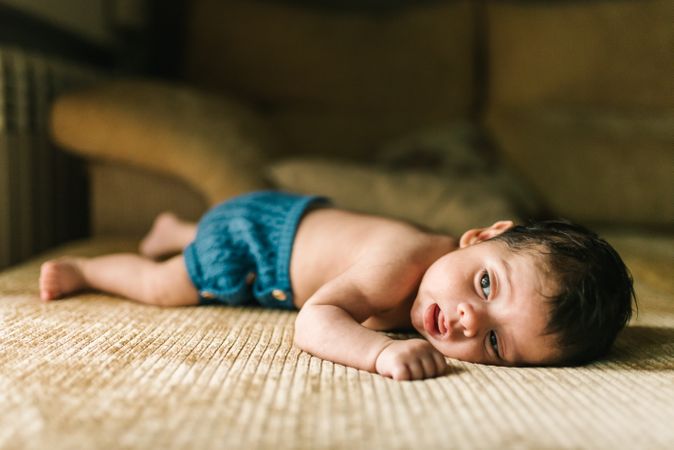innocent newborn baby in back lying on sofa at home
