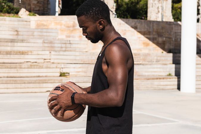Serious Black man with basketball on sports ground