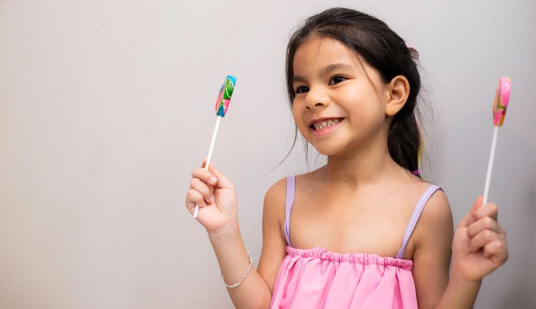 Girl in pink dress holding lollypops